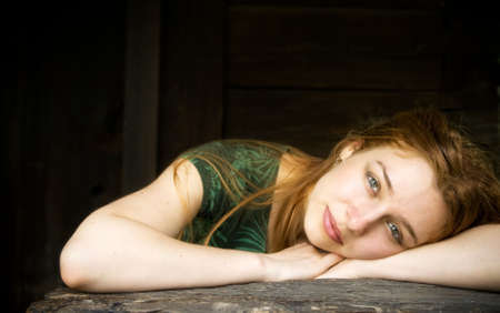 Beautiful young woman relaxing in front of a wooden houseの写真素材
