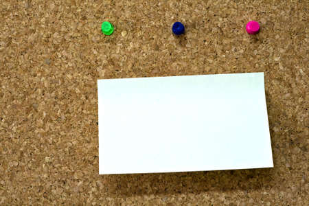 Blank reminder on wooden board and three colorful pinsの写真素材