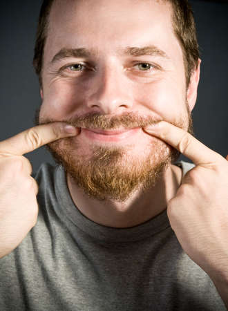 Young man keeping a fake smile on his faceの写真素材