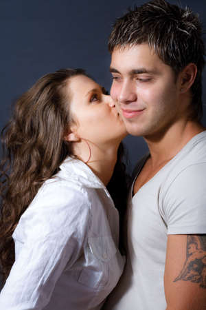 Happy playful couple: young woman kissing her loverの写真素材