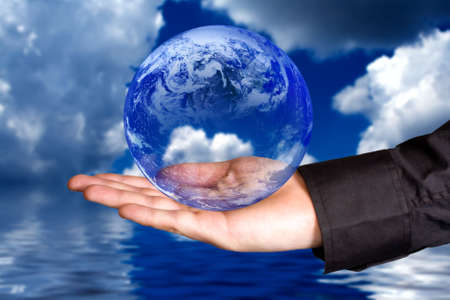 Protect the environment concept: human hand holding the Earth with clouds and water in backgroundの写真素材