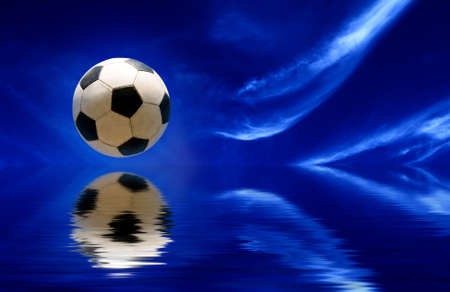 Soccer ball reflecting in water and blue sky as backgroundの写真素材