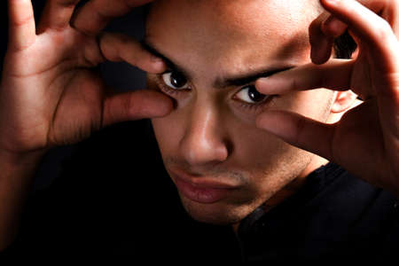 Scary man in the dark with fingers near eyesの写真素材