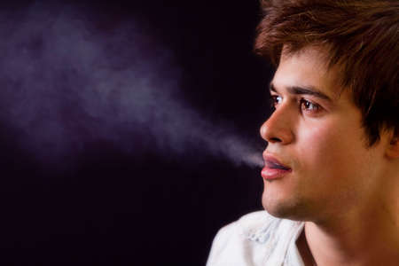 Cool young man with smoke coming out of his mouthの写真素材