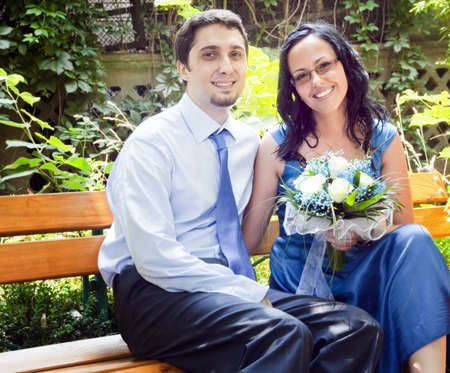 Portrait of happy couple sitting on park benchの写真素材