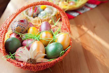 Easter painted eggs in traditional basket on tableの写真素材