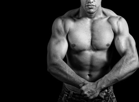 Big athletic man showing his muscles over black backgroundの写真素材