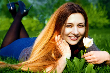 Portrait of happy young woman with tulip in fresh grassの写真素材
