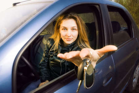 Cute woman offering keys to new carの写真素材