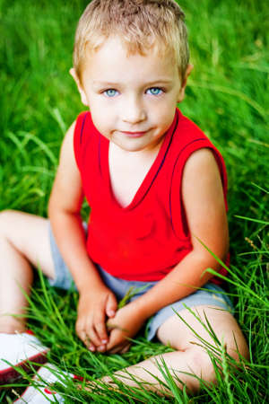 Portrait of cute serene kid on fresh green grassの写真素材