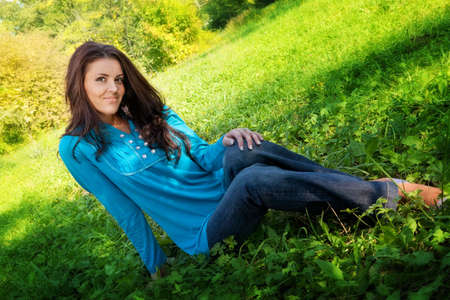 Young cute woman resting on green summer grassの写真素材