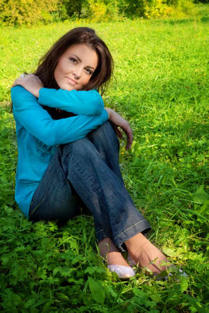 Serene beautiful young woman resting on green grassの写真素材