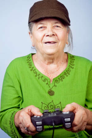 Happy senior woman playing video games with gamepadの写真素材