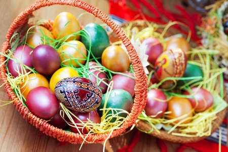 Easter colorful painted eggs in basket on tableの写真素材
