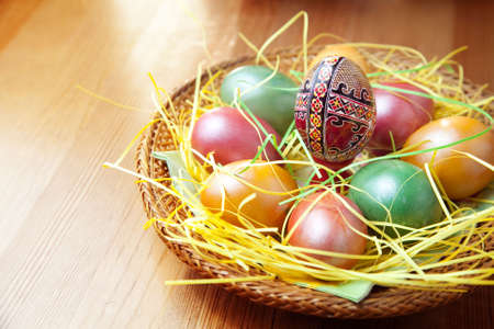 Easter painted eggs in traditional basket on tableの写真素材