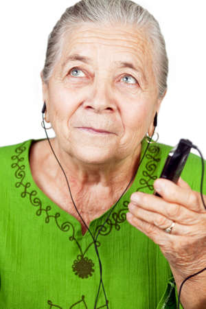 Senior old woman listening music at mobile phoneの写真素材