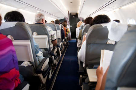 Interior of airplane with passengers on seatsの写真素材
