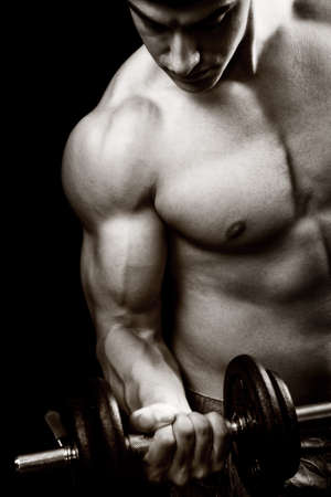 Gym and fitness concept - bodybuilder and dumbbell over blackの写真素材