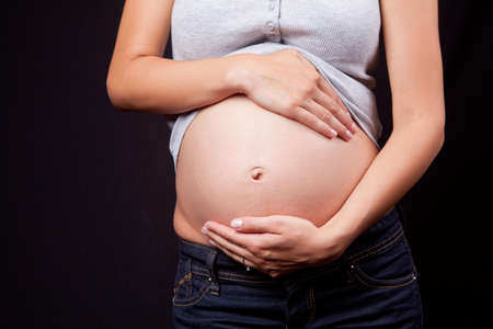 Beautiful belly of pregnant woman over black backgroundの写真素材