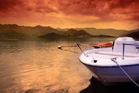 Boat on lake and colorful sunset orange skyの写真素材