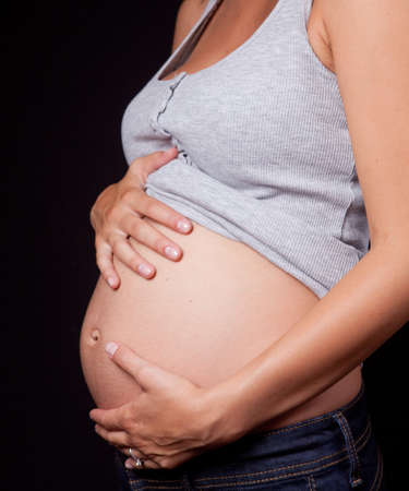 Belly of pregnant woman over dark backgroundの写真素材