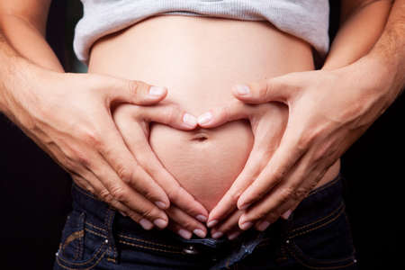 Heart shaped hands of pregnant woman and her husbandの写真素材