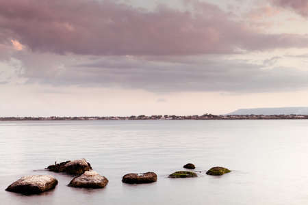 Peaceful seascape - water sky and rocks at duskの写真素材