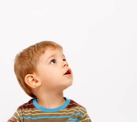 Boy in winter clothes looking up on white backgroundの写真素材
