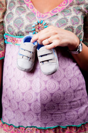 Pregnant woman holding baby shoesの写真素材