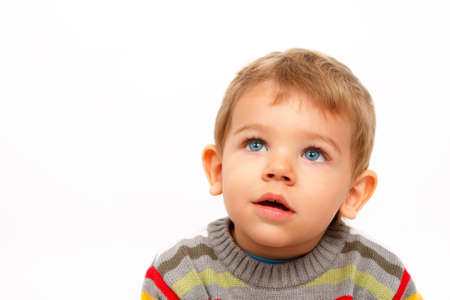 Cute boy in winter clothes looking up amazedの写真素材