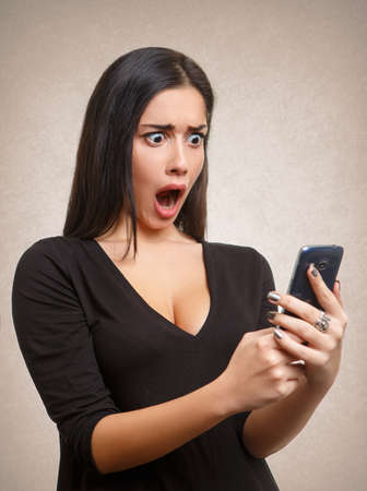 Young woman shocked by mobile phone news or messageの写真素材