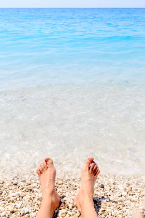 Beach holiday - male feet and summer seaの写真素材