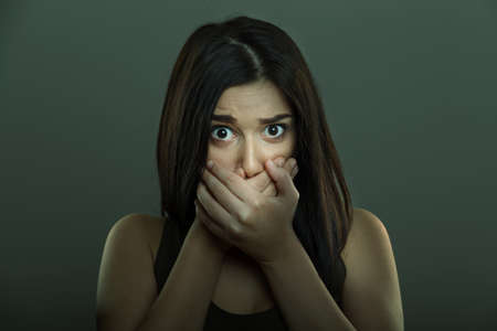 Scared woman with fear expression and hands covering mouthの写真素材
