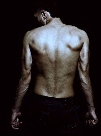 Sexy male with muscular lean back posing fashion over dark backgroundの写真素材