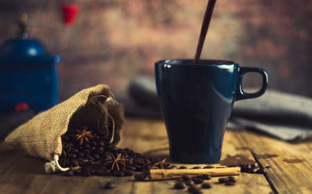 black coffee cup on old wood with coffee beans and old grinder