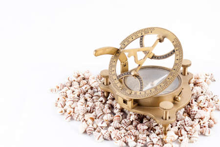 Old nautical sundial compass with shells isolated in a white background