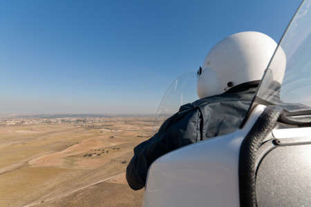 An autogyro is flying to a little villageの写真素材