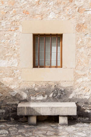 A stone bench under a window in a stone block wall of a traditional house in village of Pedraza, Spainの写真素材