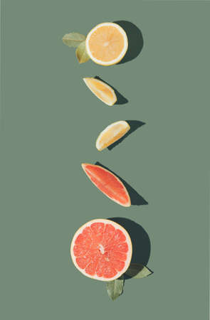 Creative layout made of citrus fruits on the green background. Fresh lemon and grapefruit flat lay concept.の写真素材
