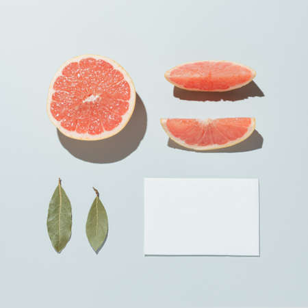 Neatly arranged fruits with leaves and paper. Minimal flat lay on pastel grey background.の写真素材