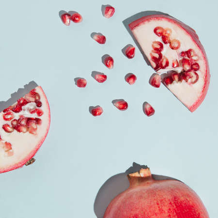 Creative pomegranate layout made of seeds and pomegranate cut open on the pastel blue background. Fresh fruit minimalism concept.の写真素材
