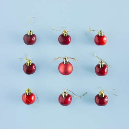 Red christmas bauble and cherries pattern on a blue pastel background. Flat lay new year concept.の写真素材