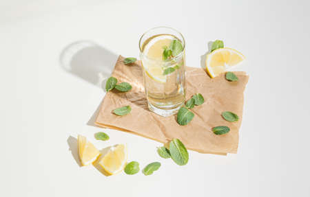 Fresh layout of mint leaves, lemon slices and drink in a glass. Cocktail spring concept with shadow. Bright drink arrangement.の写真素材