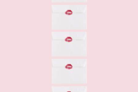 Creative pattern made of a white envelope with red kiss. Minimal love composition on a pink background.の写真素材