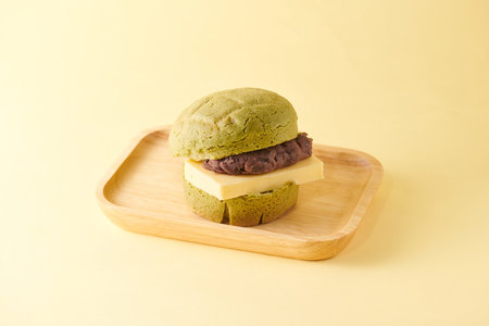 Green tea macaroon on wooden plate on yellow background, sweet dessert