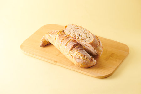 Ciabatta bread on wooden cutting board over yellow background.の写真素材