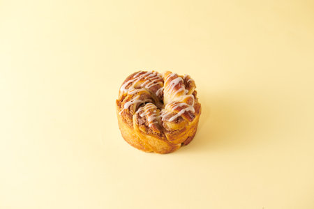 Cinnamon roll on yellow background. Sweet bun with raisins.