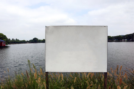 Along the park's lakeside, there are signs reminding people to be safeの写真素材