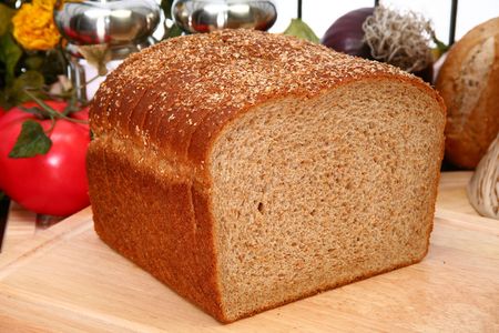 Whole wheat bread sliced on cutting board in kitchen or deli.