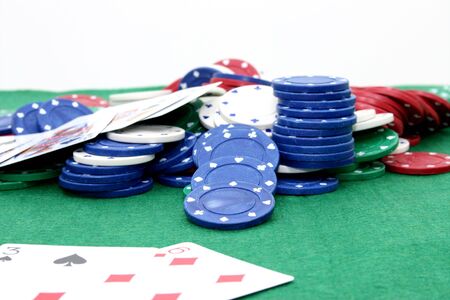 Poker chips and cards on a green felt top table.  Focus on blue chip in middle.
